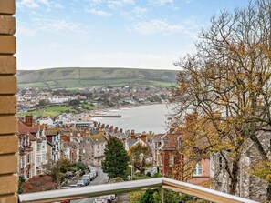 A coastal town with a view of the sea, terraced houses, and a prominent stone building. - 2 Bed in Swanage (oc-93542) (Swanage)