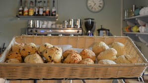 Un angolo cottura con un cesto di prodotti da forno assortiti, una sveglia appesa al muro e diversi elettrodomestici.