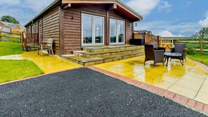A wooden cabin with a patio, outdoor seating, and a view of the surrounding landscape. - 4 Bed in Shrewsbury (oc-93398) (Sheinton)