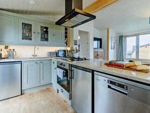 A modern kitchen with stainless steel appliances, a dishwasher, and a large window providing natural light.