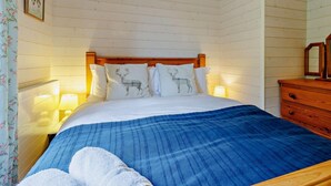 A bedroom with a wooden headboard, a bed with white bedding and blue striped blanket, a wooden dresser, and a hanging clothes rack. - 4 Bed in Shrewsbury (oc-93398) (Sheinton)