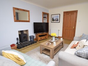 Ein Wohnzimmer mit Kamin, Fernseher, Couchtisch und Sofa.
