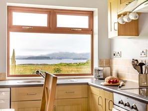 A kitchen with a large window, a toaster, and a loaf of bread on the counter.