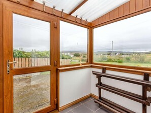 Ein Eckzimmer mit einer Holzbank, großen Fenstern und Blick auf eine ländliche Landschaft.