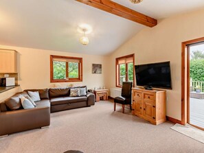 A living room with a sofa, TV, wooden cabinet, and large windows. - 3 Bed in York (oc-93206) (Elvington)