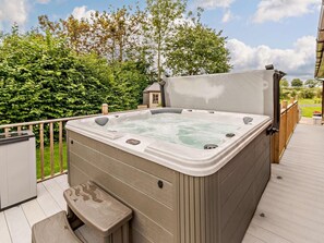A hot tub on a wooden deck with a view of trees and a house in the background. - 3 Bed in York (oc-93206) (Elvington)
