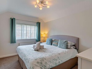A bedroom with a bed, a bedside table, a lamp, and a window with curtains. - 4 Bed in Weymouth (oc-86369) (Weymouth)