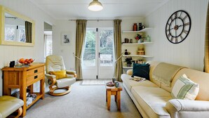 Ein gemütliches Wohnzimmer mit einer Couch, einem Sessel, einem Holztisch und einem kleinen Couchtisch.