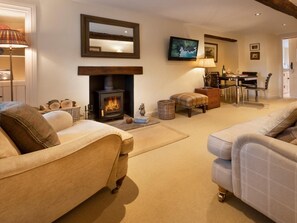 Ein gemütliches Wohnzimmer mit Kamin, Sofas, einem Fernseher und einem Essbereich.