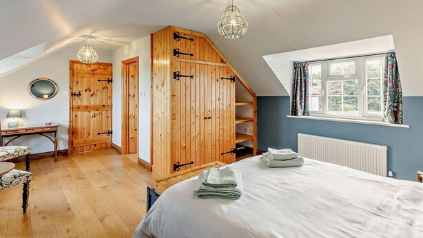 A bedroom with a bed, a desk, a chair, a wardrobe, and a window with curtains. - 3 Bed in Market Rasen (oc-93253) (Ranby)