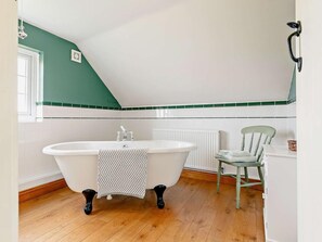 A bathroom with a freestanding bathtub, a radiator, a chair, and a window. - 3 Bed in Market Rasen (oc-93253) (Ranby)