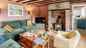 A cozy living room with a green sofa, a wooden coffee table, a fireplace, and a television. - 3 Bed in Market Rasen (oc-93253) (Ranby)