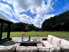 An outdoor dining area with a table set for two, a sofa, and a gazebo in the background. - 3 Bed in Brecon (oc-93680) (Llandefalle)