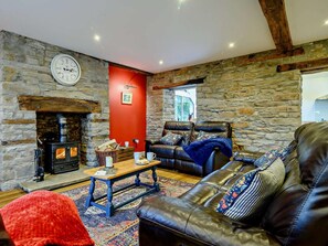A cozy living room with a stone wall, a fireplace, a leather sofa, and a wooden coffee table. - 3 Bed in Brecon (oc-93680) (Llandefalle)