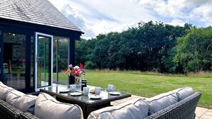 An outdoor seating area with wicker furniture, a glass table, and a flower vase. - 3 Bed in Brecon (oc-93680) (Llandefalle)