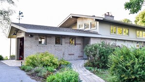 Een modern huis met een gevel van natuursteen, een schuin dak en een pad van baksteen dat naar de ingang leidt.