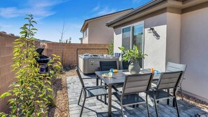 Une terrasse avec une table et des chaises, un jacuzzi et un barbecue.