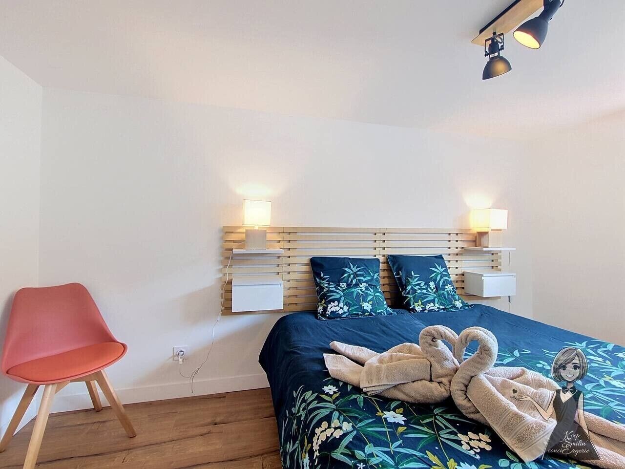 Ein Schlafzimmer mit einem Bett, zwei Nachttischen, einem roten Sessel und einer Wandlampe.