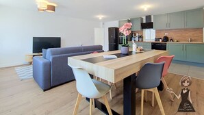 Et moderne køkken med spiseplads, en sofa og et fjernsyn.