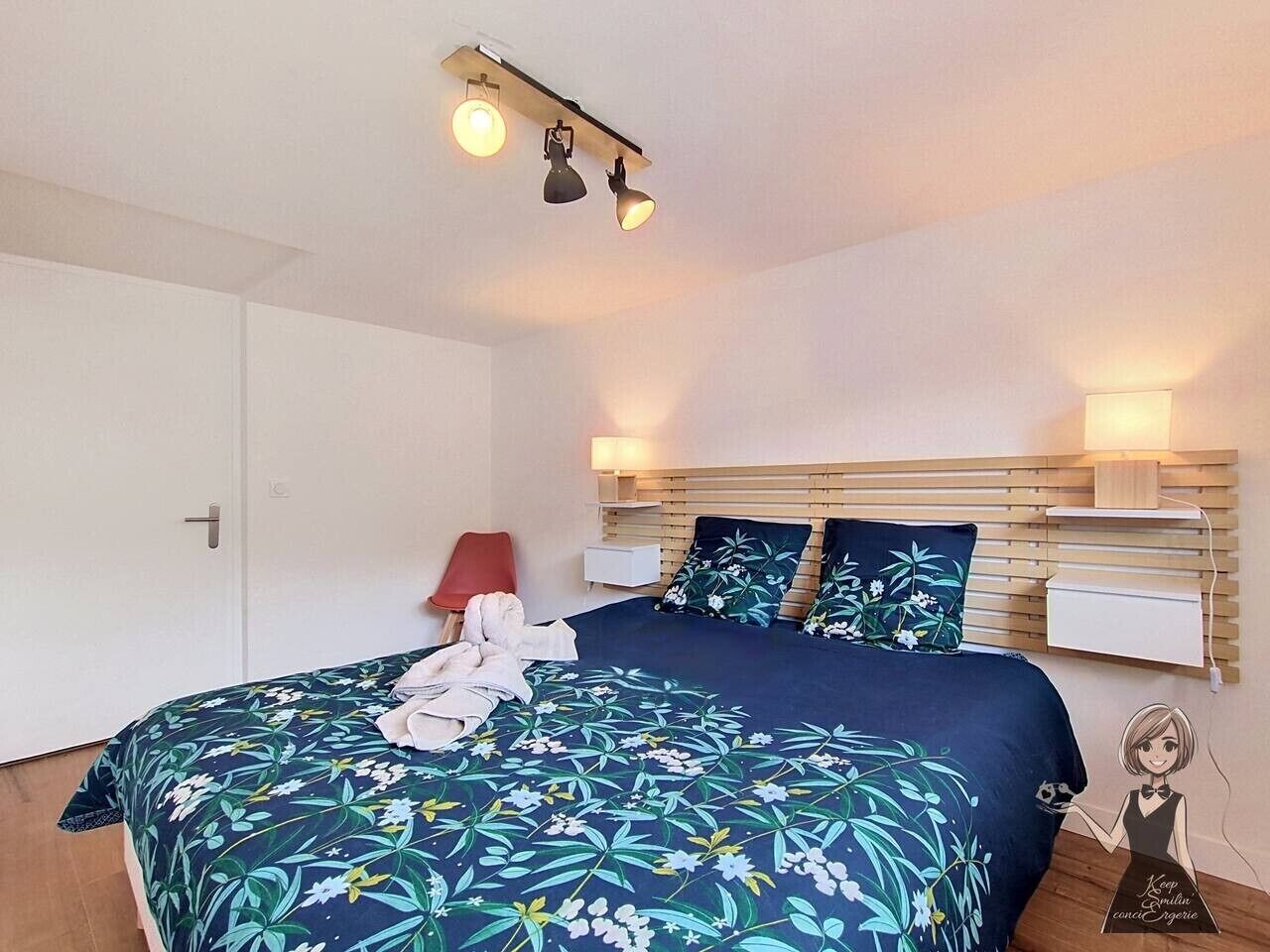 A bedroom with a bed, bedside tables, a nightstand, a lamp, and a wall-mounted shelf.