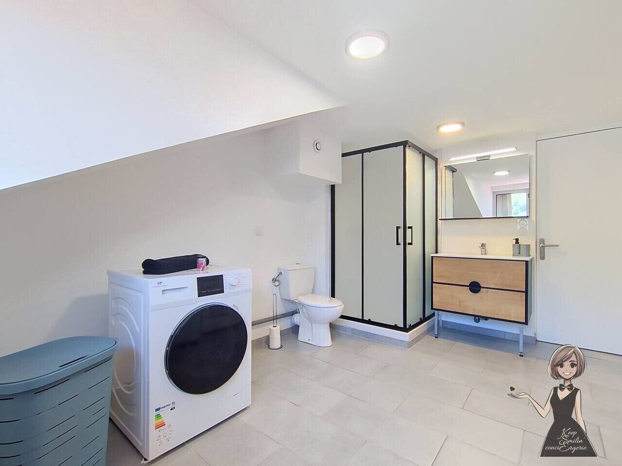 A modern bathroom with a washing machine, toilet, and a glass shower enclosure.