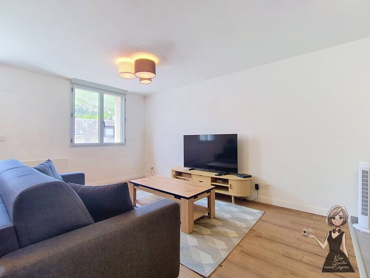 En moderne stue med en sofa, et sofabord, et fjernsyn og et lille bord med en lampe.