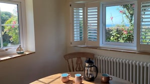 Una habitació amb una taula, tres tasses de cafè, una cafetera i una cadira.