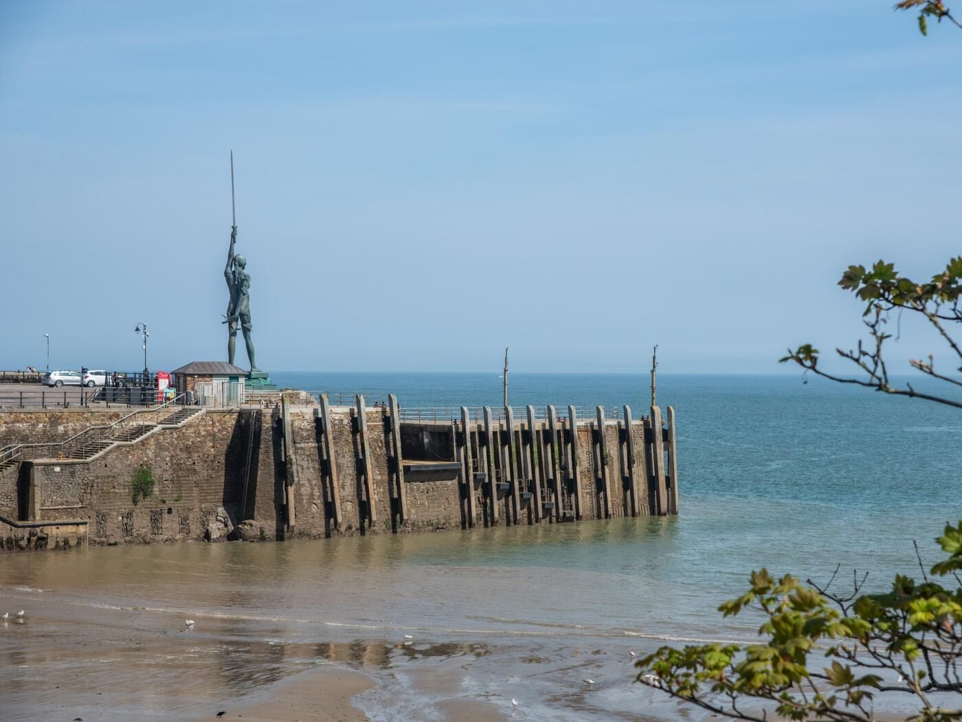 Un paysage côtier avec une statue, une jetée et une plage.