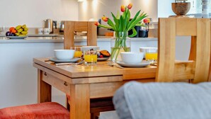 Ein Frühstückstisch gedeckt mit Schüsseln, Gläsern und einer Tulpenvase.