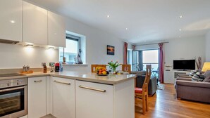 Eine moderne Küche mit weißen Schränken, einem eingebauten Backofen und einem Essbereich mit Tisch und Stühlen.