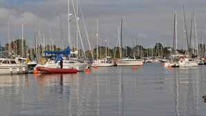 Una marina con diverse barche a vela ormeggiate, acqua calma e cielo sereno.
