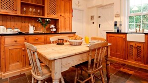 Una cucina in legno con un tavolo da pranzo, sedie e una finestra con tende.