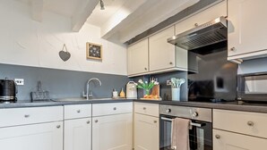 Eine moderne Küche mit weißen Schränken, einem Backofen, einer Mikrowelle und einer Kaffeemaschine.