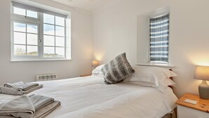 Ein Schlafzimmer mit einem Bett, zwei Nachttischlampen, einem Fenster mit Aussicht und einer Heizung.