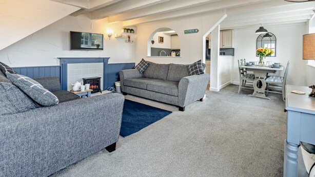Ein gemütliches Wohnzimmer mit Kamin, einer Couch und einem Essbereich mit Tisch und Stühlen.