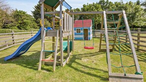 Ein Spielplatz mit Rutsche, Schaukel und Klettergerüst.