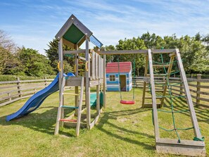 A playground with a slide, swing set, and climbing structure. - 2 Bed in Bideford (oc-46824) (Pusehill)