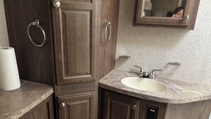 A bathroom with a wooden vanity, a sink, and a mirror. - Quaint 1 bed RV, on the lake. Sleeps 6-7 (McLoud)