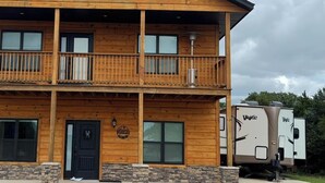 A two-story wooden building with a balcony, a front door, and a sign. - Quaint 1 bed RV, on the lake. Sleeps 6-7 (McLoud)