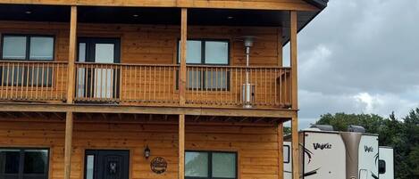 A two-story wooden building with a balcony, a front door, and a sign.