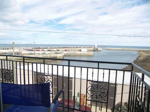 A balcony with a view of a coastal area, including a pier and parked cars. - 3 Bed in Seahouses (oc-cn097) (Seahouses)