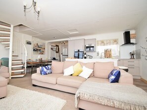 A modern living room with a sofa, a dining area, a kitchen, and a staircase. - 3 Bed in Seahouses (oc-cn097) (Seahouses)