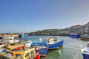 A harbor with multiple boats docked, a pier, and buildings in the background. - 3 Bed in Seahouses (oc-cn097) (Seahouses)