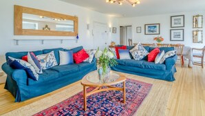 Ein Wohnzimmer mit blauem Sofa, rundem Couchtisch und einem gemusterten Teppich.