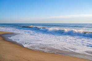 A beach with waves, clear sky, and a calm sea. - Ocean Side Condo | Steps to the Beach (Ocean City)