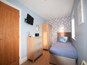 A bedroom with a bed, a wooden wardrobe, a desk with a computer, a wall-mounted TV, and patterned wallpaper. - 2 Bed in Seahouses (oc-cn166) (Seahouses)
