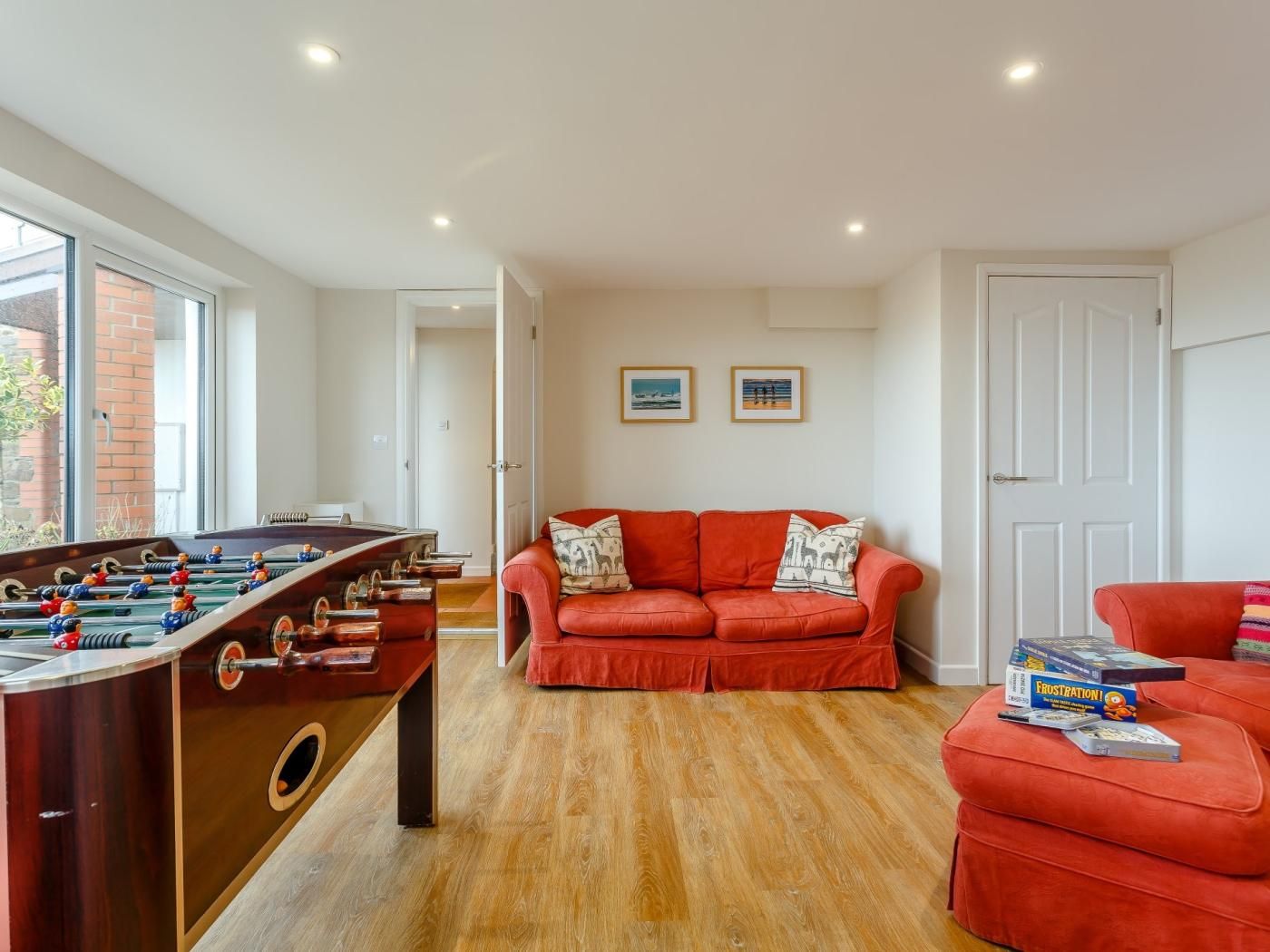 A room with a foosball table, a red sofa, and a door.
