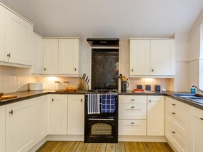 A kitchen with white cabinets, a black oven, and a granite countertop. - 4 Bed in Bideford (oc-66659) (Northam)