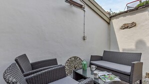Een terras met rieten meubels, een tafel en een decoratieve wandversiering.
