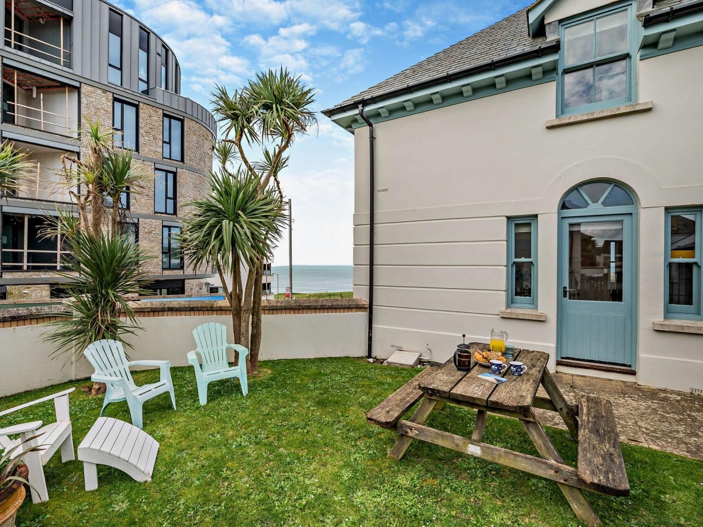 A coastal property with a grassy patio, outdoor seating, and a view of the sea.